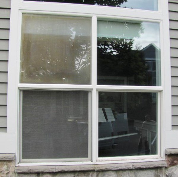 Exterior view of a four-square window grid showing two rightside panes shiny & polished and two leftside panes dull & unpolished.